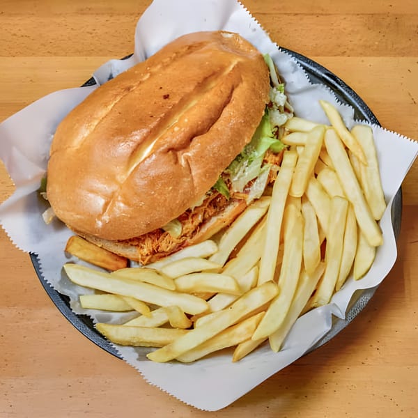 A Latin-American torta sandwich with shredded meat and lettuce, served with a side of french fries.