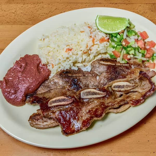 Grilled short ribs, rice, refried beans, pico de gallo, and a lime wedge on a plate.